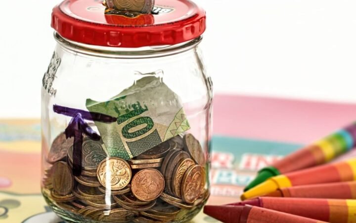 GlassPersonal finance tips for beginners featuring budgeting, saving, investing, and wealth-building concepts savings jar with cash and coins illustrating how to build wealth with $100 a month